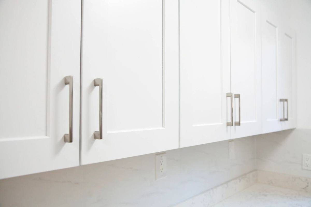 Close view of white kitchen cabinets with brushed metal handles